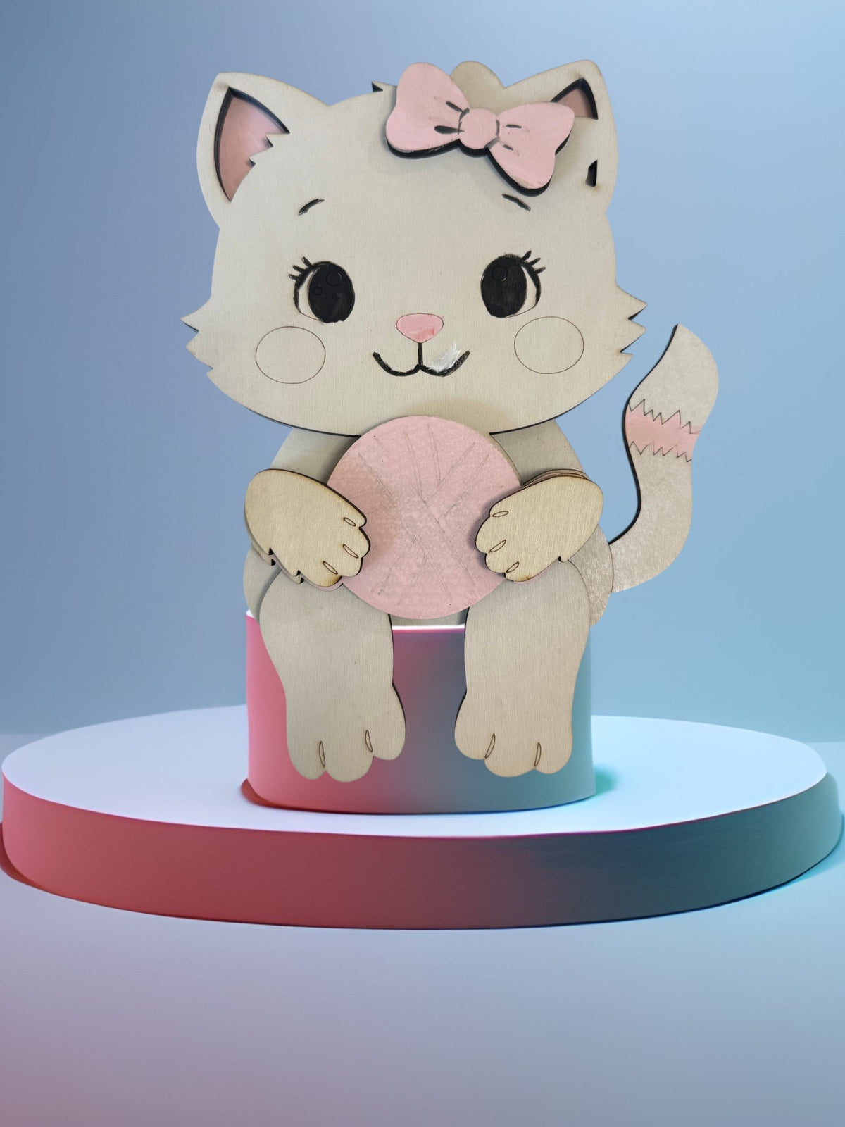 Wooden kitten shelf sitter with a pink bow holding a ball of yarn